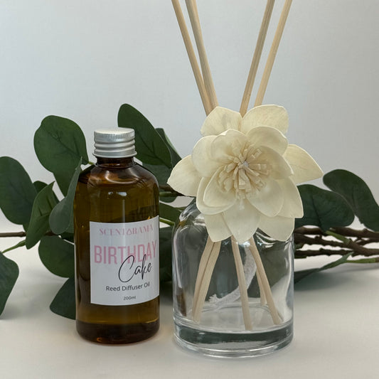 Reed diffuser set with bottle labeled 'Birthday Cake' and decorative flower on a light background