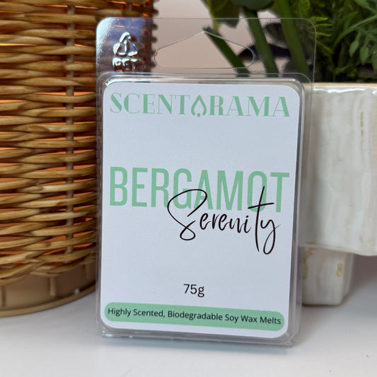 A packaged wax melt product labeled SCENTARAMA BERGAMOT Serenity, 75g, standing upright on a white surface with a wicker wax warmer and potted plants in the background.
