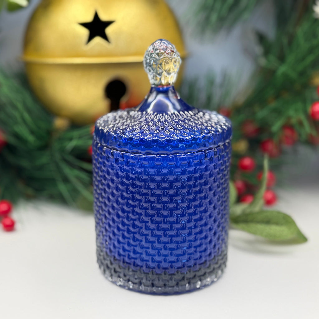 Blue decorative jar with a lid on a white surface with Christmas decorations in the background