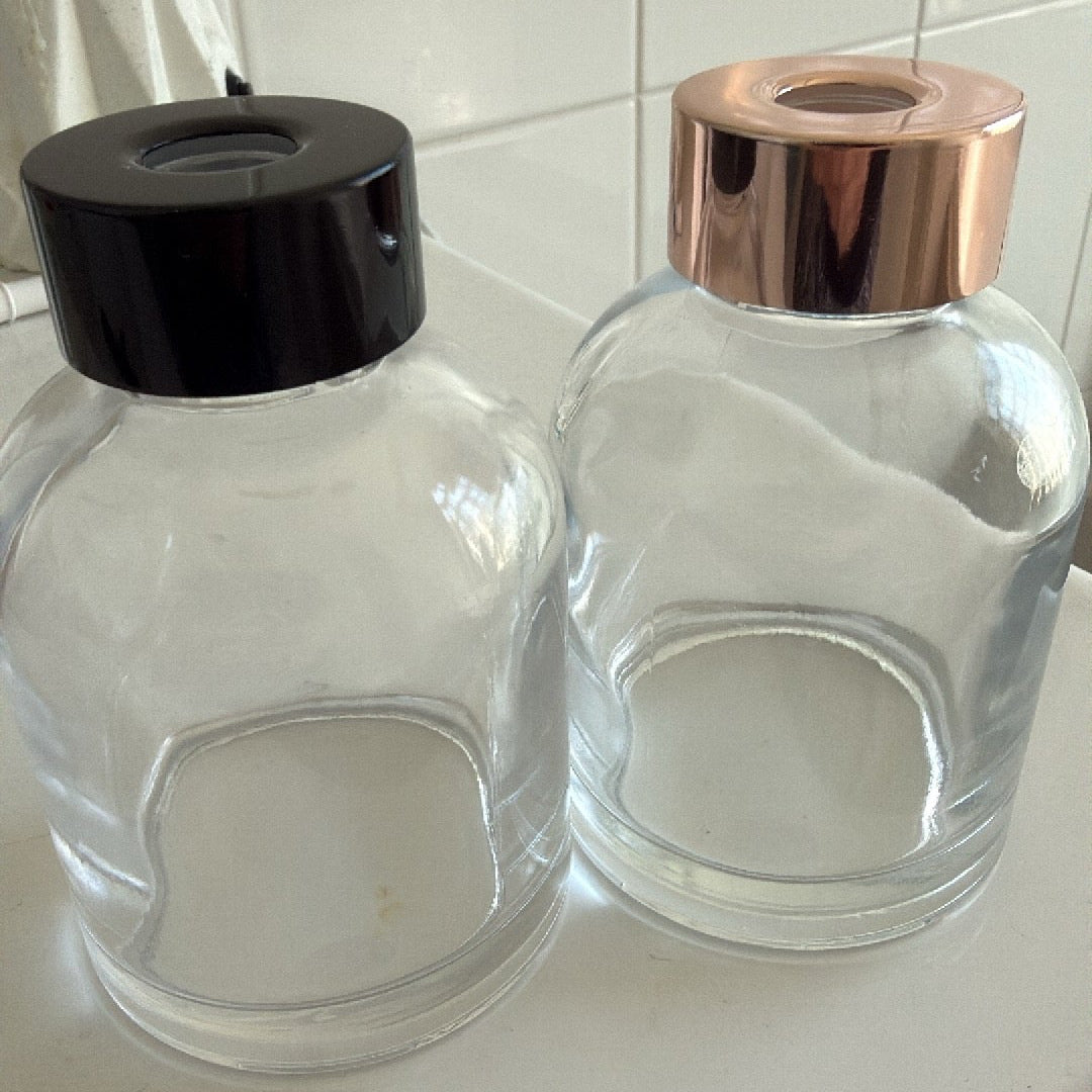 Two glass containers with black and rose gold lids on a white surface.