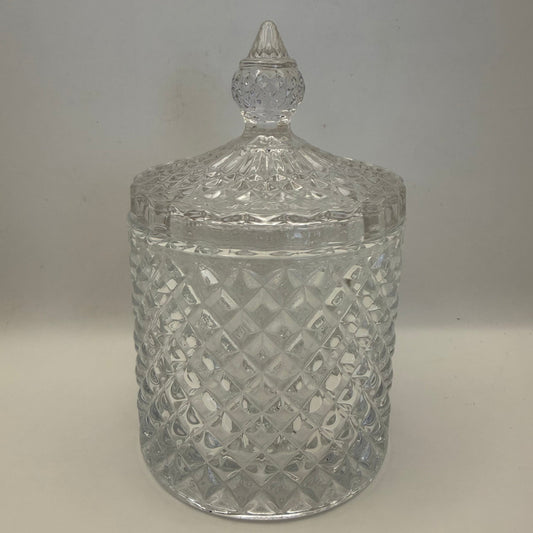 Clear glass candle jar with diamond pattern and textured lid on a plain background