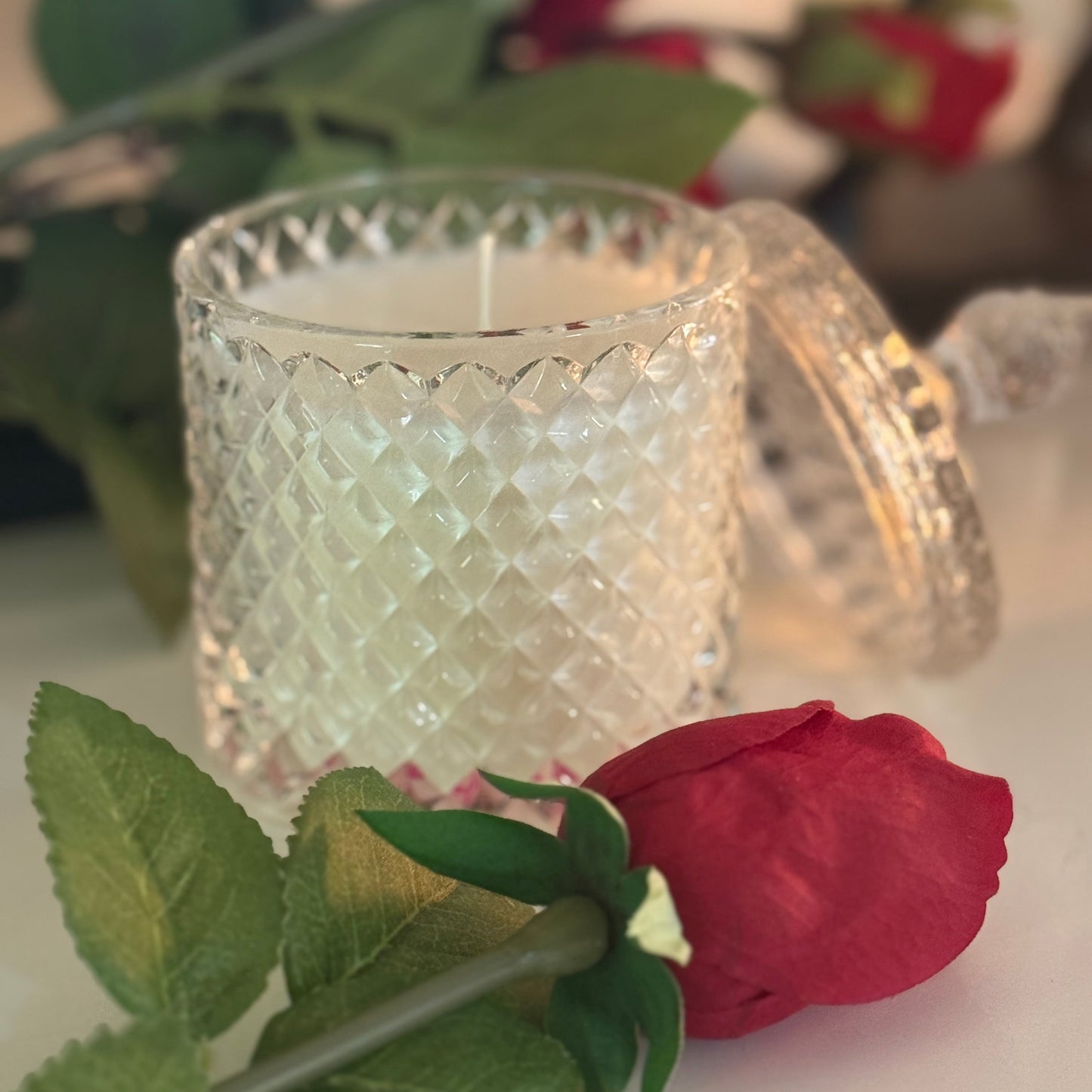 Decorative glass candle holder with a red rose in the foreground