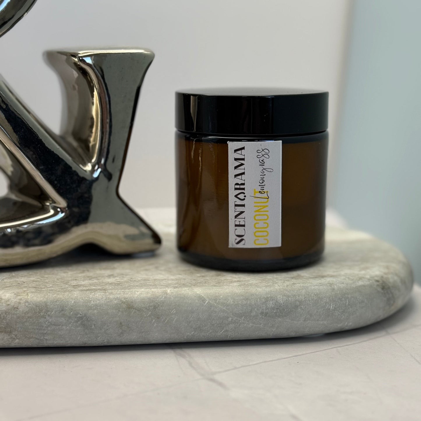 Amber Candle jar in Coconut Lemongrass Scent featuring a scentarama label on a white surface