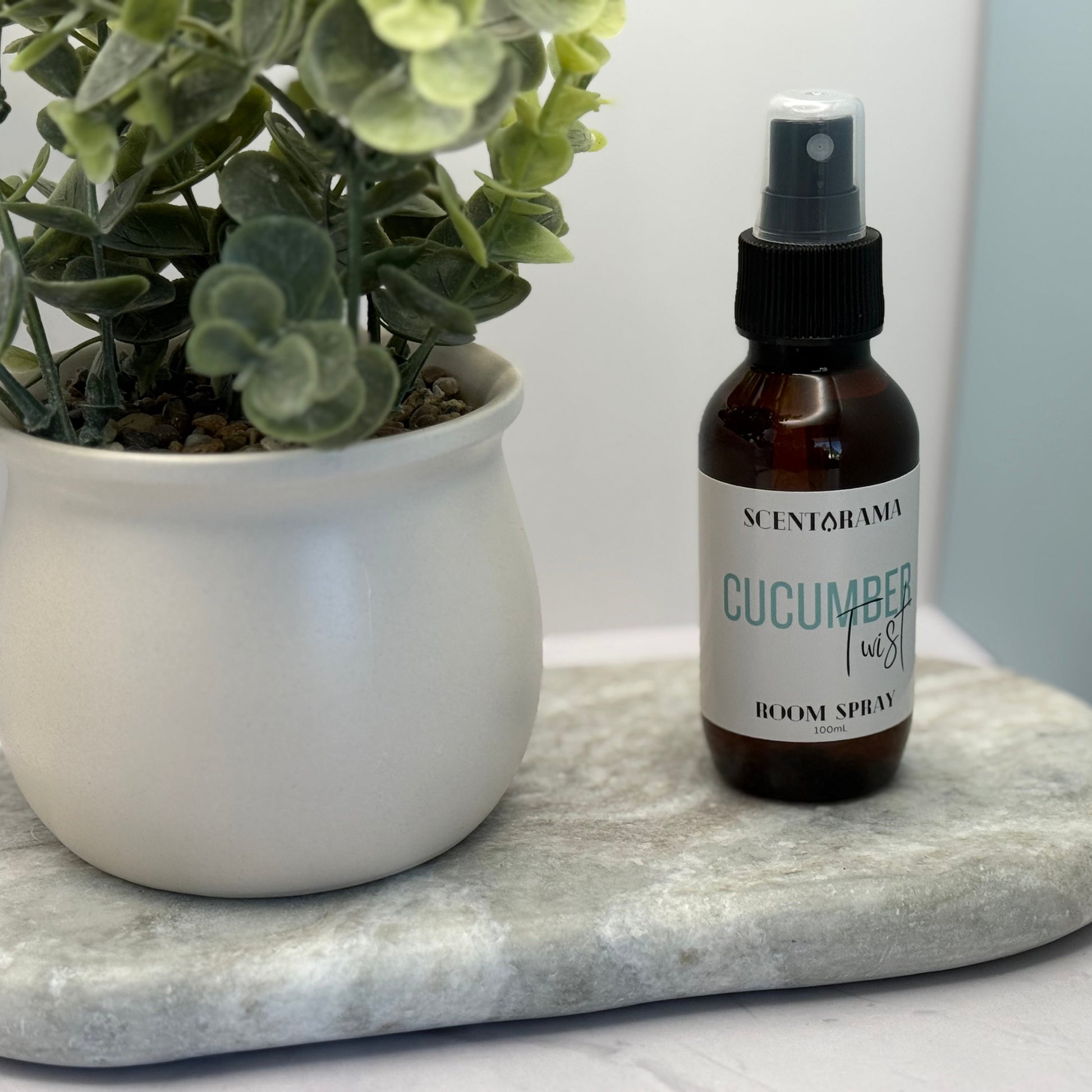 Bottle of cucumber bloom spray on a marble tray with a plant