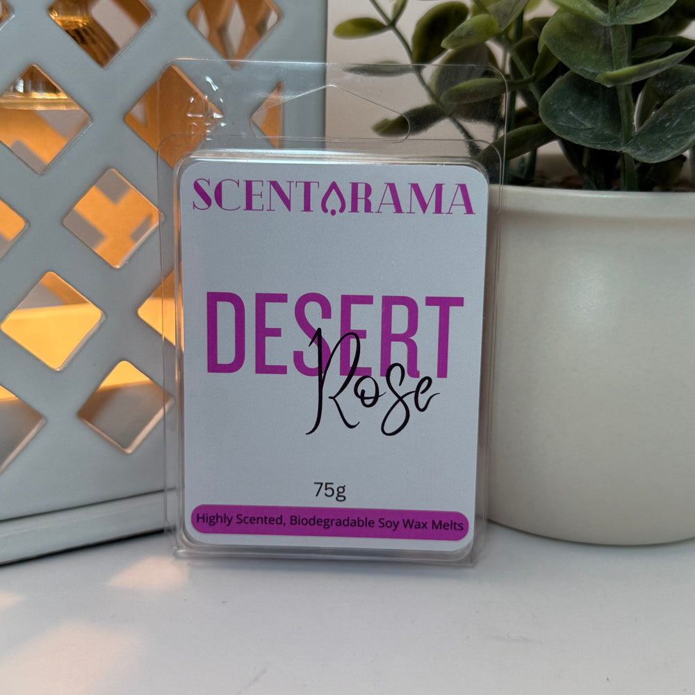 A package of Scentarama Desert Rose soy wax melts, 75g, displayed on a white surface with a decorative white lattice screen and a potted green plant in the background.