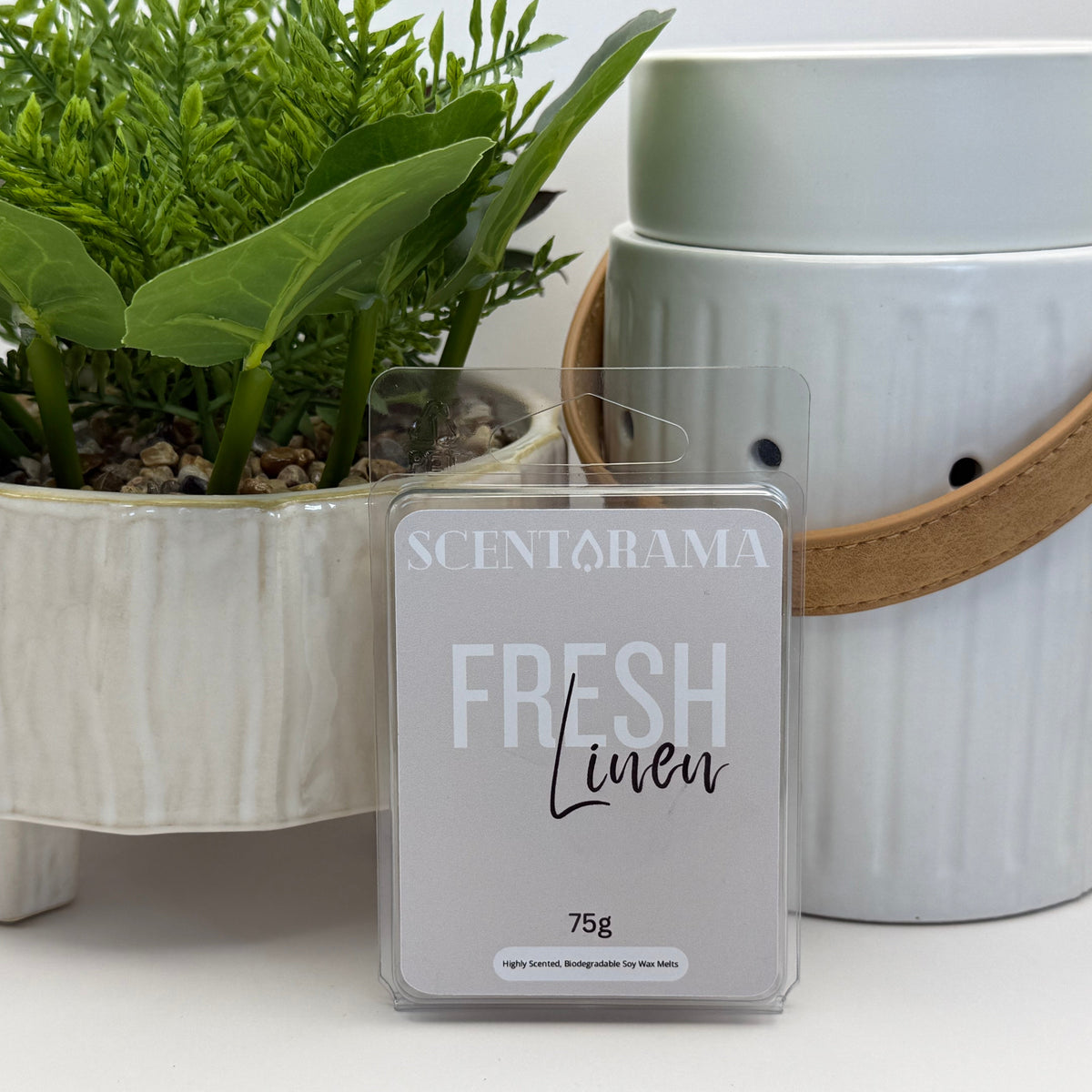 Fresh linen soy wax melts by scentarama propped up against the leather handle warmer and a potted plant