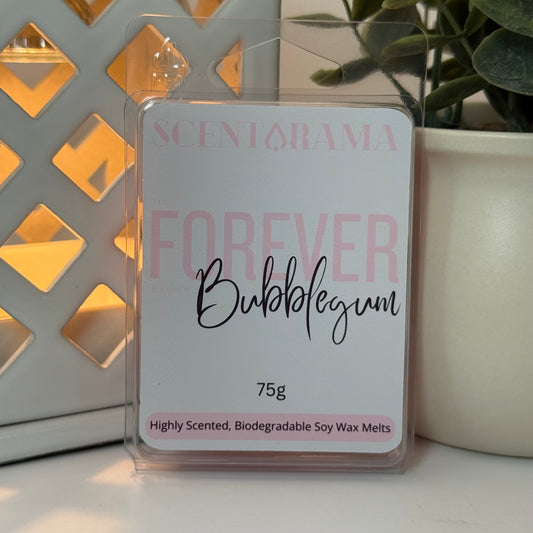 A packaged Scentarama 'Forever Bubblegum' soy wax melts, 75g, in a clear plastic clamshell package. The label is white with pink text and black cursive writing, set against a background with a lit geometric candle holder on the left and a potted plant on the right.