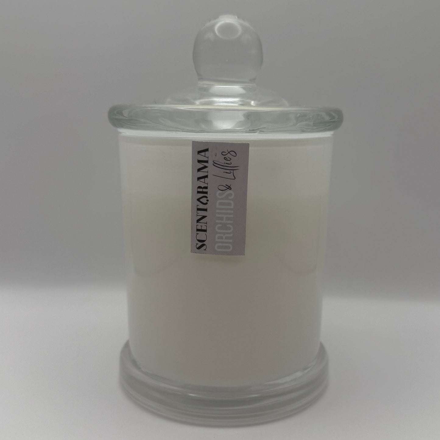 White candle in a glass jar with a label on a white background