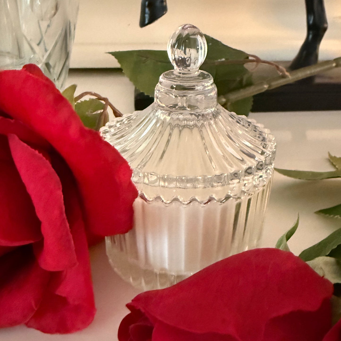 Clear scentarama glass candle dish with red flowers in the foreground