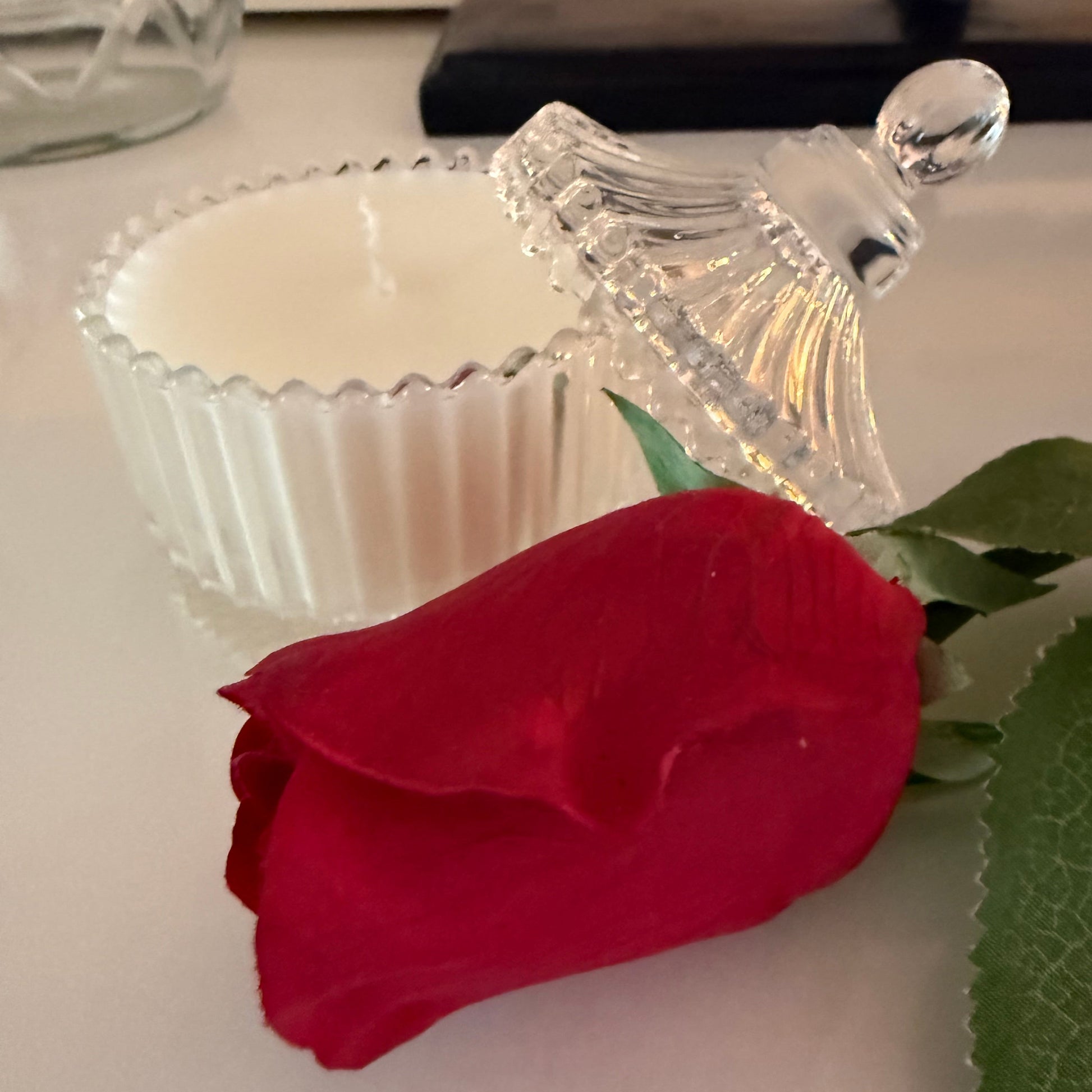 Red rose in a decorative glass holder on a white surface