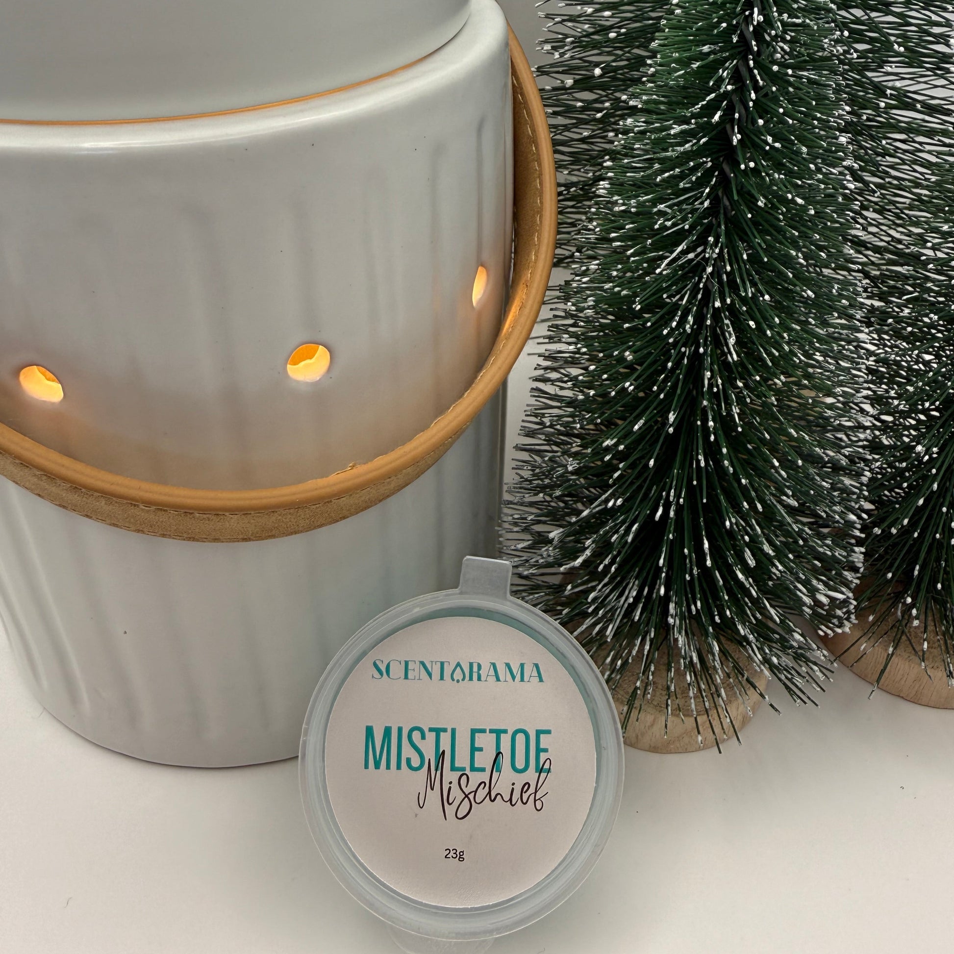 Mistletoe Mischief Soy Wax Melt Mini Pot propped up against Leather Handle Wax Melt warmer and Mini Christmas Tree table decorations
