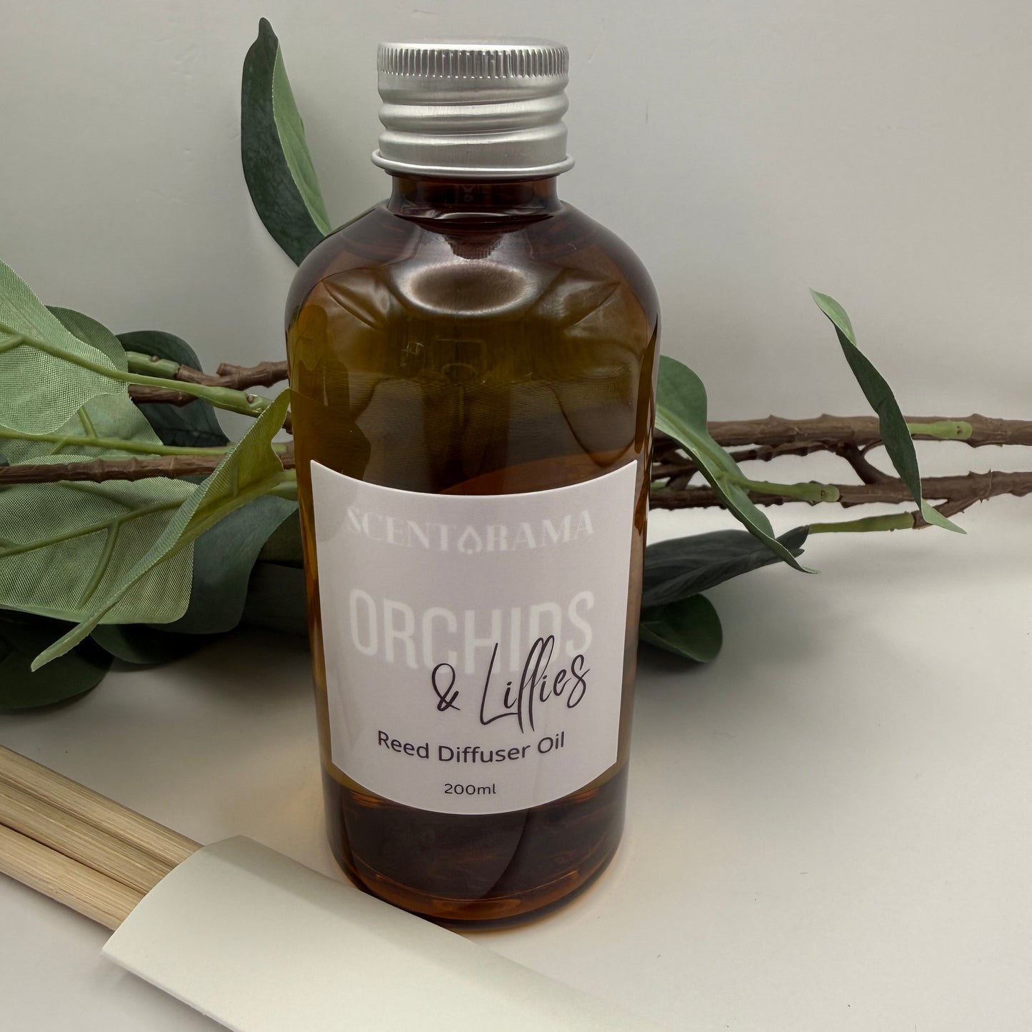 Brown bottle with a label on a white surface with green leaves