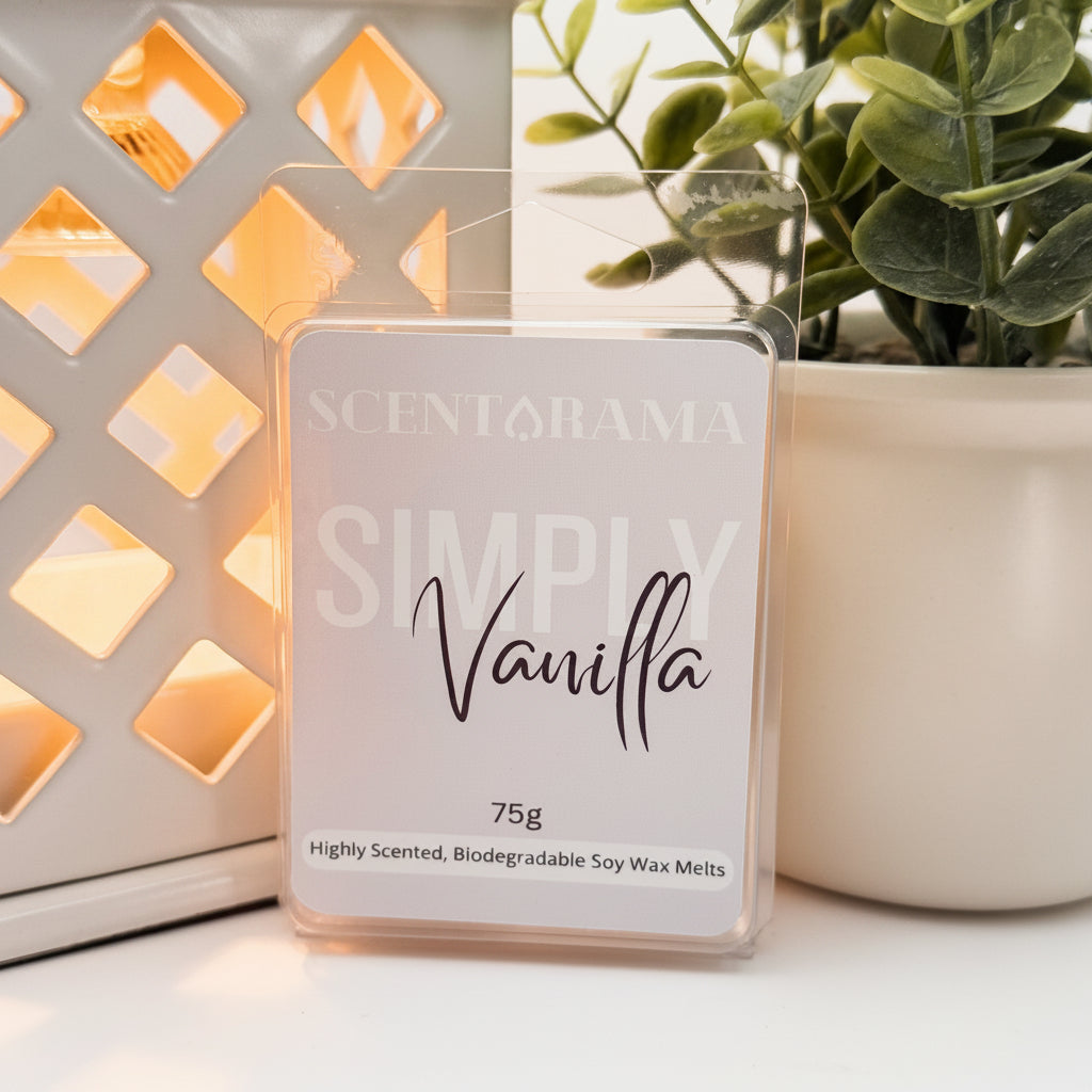 A Scentarama Simply Vanilla 75g scented wax melt in a clear plastic clamshell package, displayed on a white surface next to a lit decorative lantern and a potted plant.