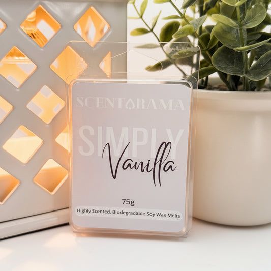 A Scentarama Simply Vanilla 75g scented wax melt in a clear plastic clamshell package, displayed on a white surface next to a lit decorative lantern and a potted plant.