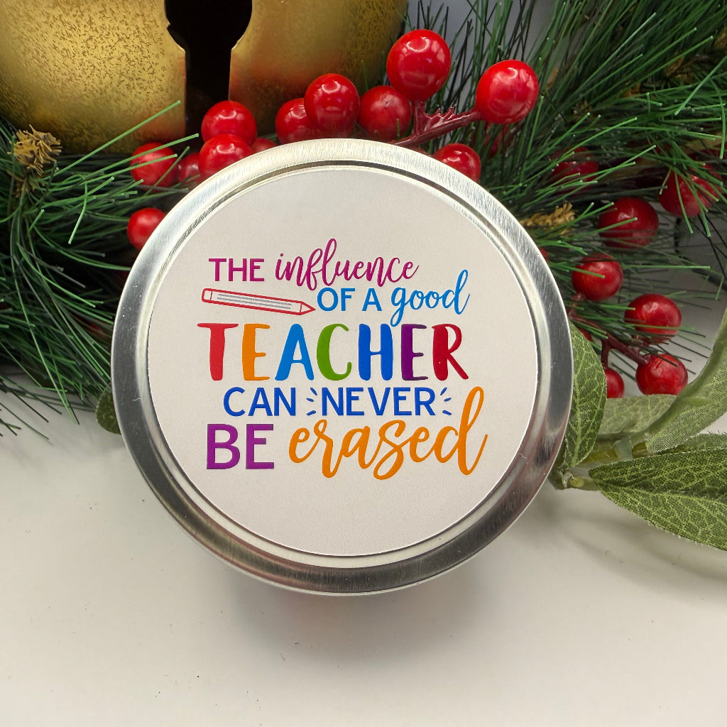 Decorative tin candle with motivational quote surrounded by Christmas decorations