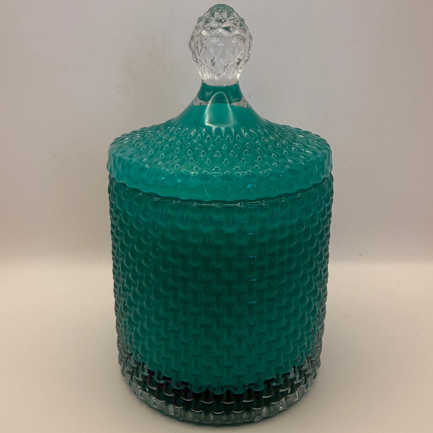 Teal textured glass Candle jar with a clear lid on a beige background