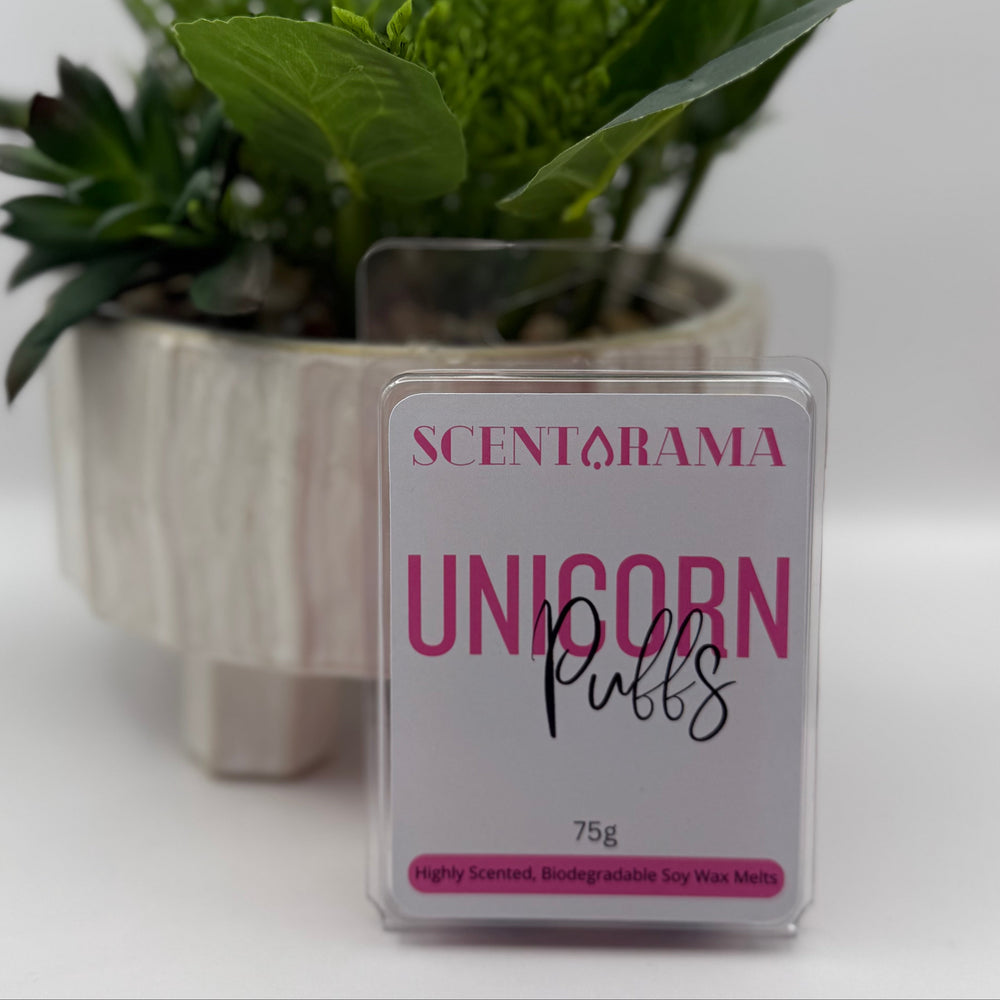 A 75g pack of Scentarama 'Unicorn Puffs' soy wax melts in a clear plastic clamshell container, set against a white background with a decorative potted green plant behind it.